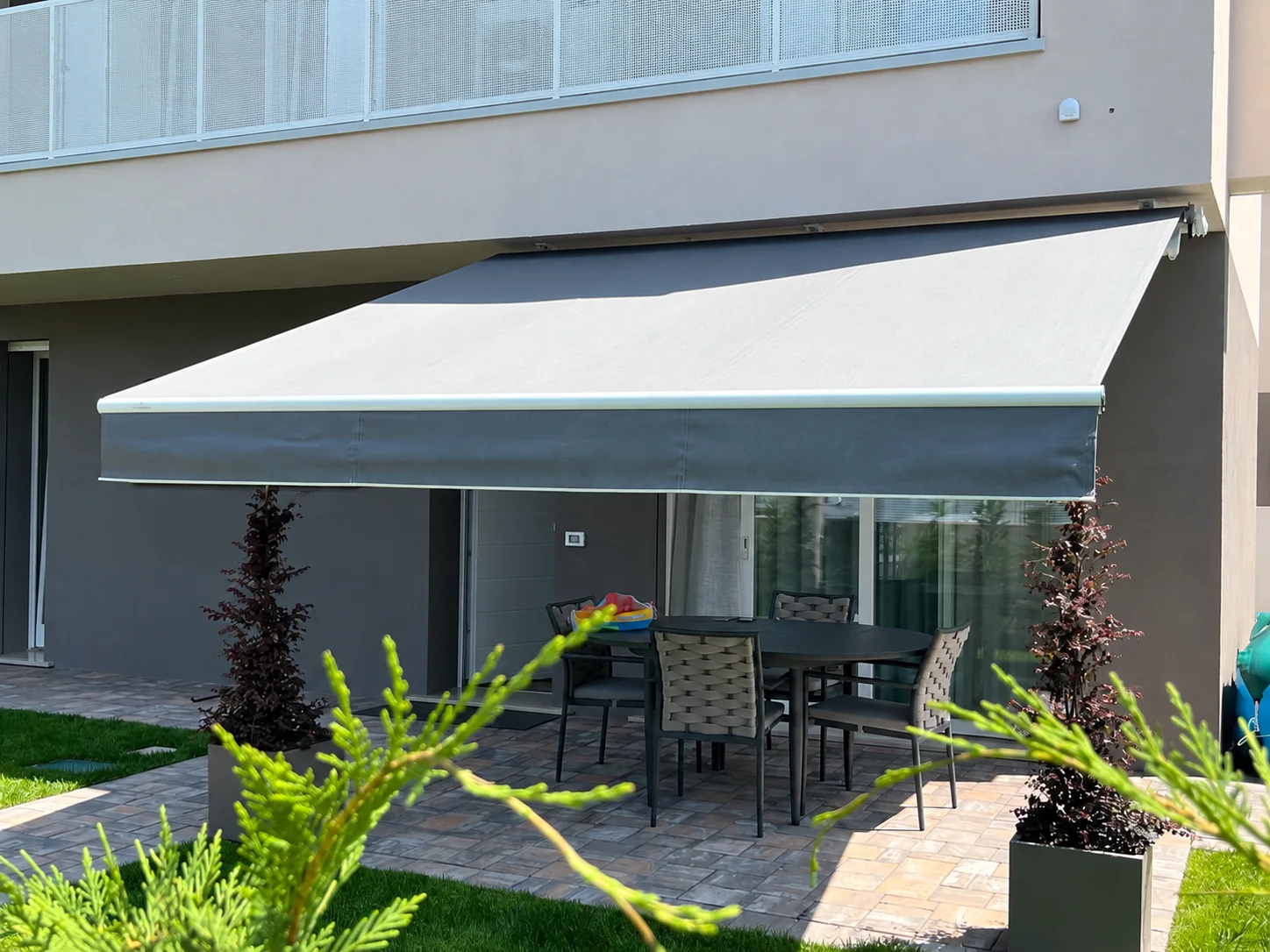 Tenda da sole grigia aperta sopra un tavolo in giardino
